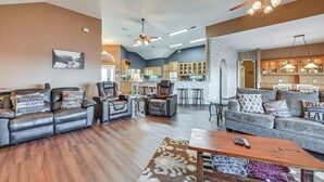 A spacious living area with leather sofas, a coffee table, and a kitchen in the background. - Boat Dock & Hot Tub: Waterfront Home in Milam! (Milam)