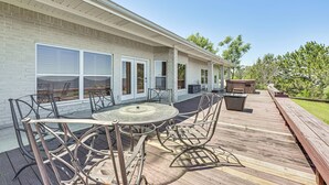 A covered patio with a round table and chairs, a brick exterior wall, and a wooden deck. - Boat Dock & Hot Tub: Waterfront Home in Milam! (Milam)