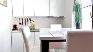 A modern kitchen with white cabinets, a stainless steel sink, and a dining table with chairs. - Chic & Green (Brussels)