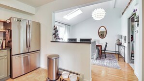 A modern kitchen with stainless steel appliances, a small dining area with a table and chairs, and a hallway leading to another room. - Family Getaway w/ Deck: 3 Mi to Lake Champlain (Colchester)