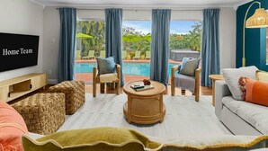 A living room with a TV, wicker ottomans, a round coffee table, and a sofa. - Sleeps 20~Heated Pool~Pickleball~Hot Tub~Fire Pit (Largo)