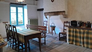 Een rustieke eethoek met houten meubels, een tafel, banken en een klein keukenhoekje met een aanrecht en apparatuur.