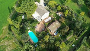 Vista aérea de una propiedad con piscina, una casa grande y vegetación circundante.