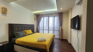 A bedroom with a bed, a TV, and a window with curtains.