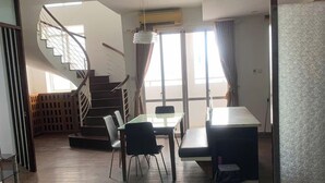 A modern interior with a dining area, a staircase, and a glass partition.