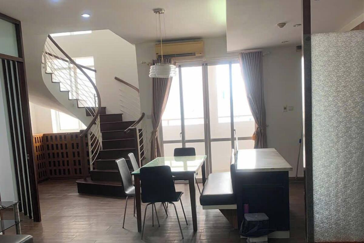 A modern interior with a dining area, a staircase, and a glass partition.