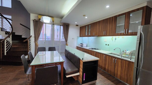 A modern kitchen with wooden cabinets, a built-in oven, and a stainless steel refrigerator.