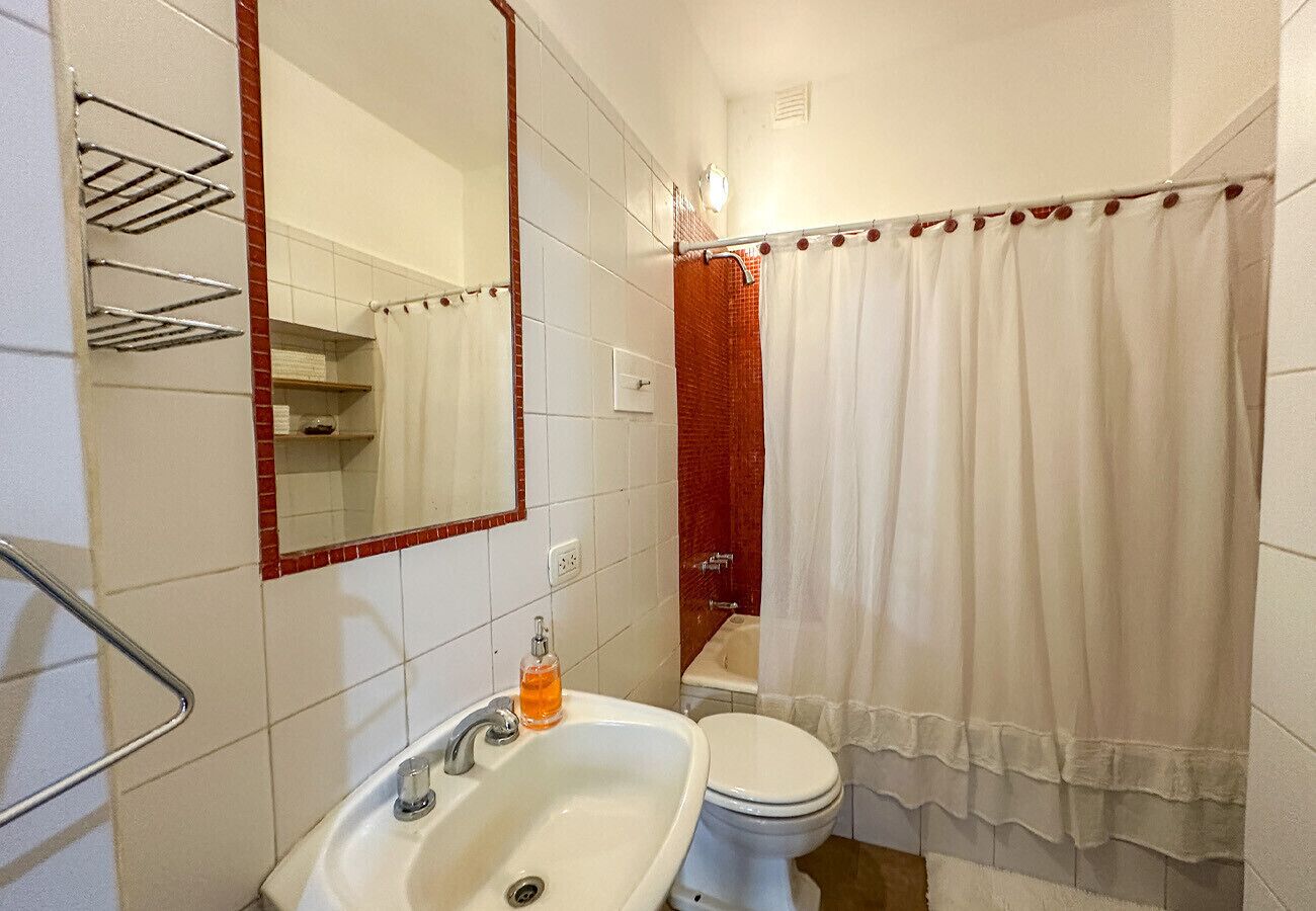 Une salle de bain avec un lavabo blanc, un miroir, des toilettes et un rideau de douche.