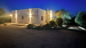 A modern building with a flat roof and a rectangular shape, illuminated by multiple lights.