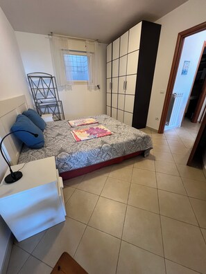 Ein Schlafzimmer mit Bett, Schreibtisch, Stuhl, Kleiderschrank und Fenster.