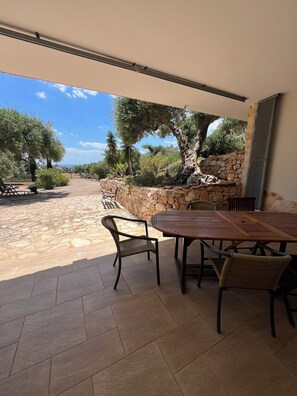 Eine Terrasse im Freien mit einer Steinmauer, einem Holztisch und Korbstühlen.