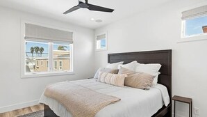 A bedroom with a bed, a ceiling fan, and a window with blinds. - 3BR + Loft Ocean View | Rooftop, Hot Tub, Parking (Newport Beach)