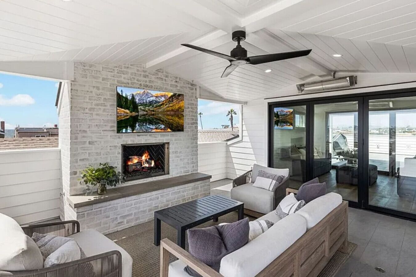 A rooftop patio with a fireplace, seating area, and a large TV screen.