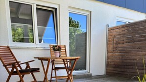 An outdoor patio with wooden furniture, a potted plant, and a view of a modern building. - Vacation apartment Allgäuherz Relax on lovingly furnished 55 sqm (Unknown)