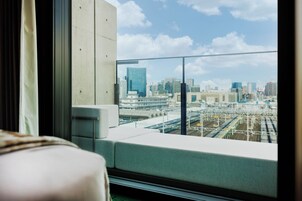 A modern hotel room with a large window offering a view of a cityscape and train tracks.