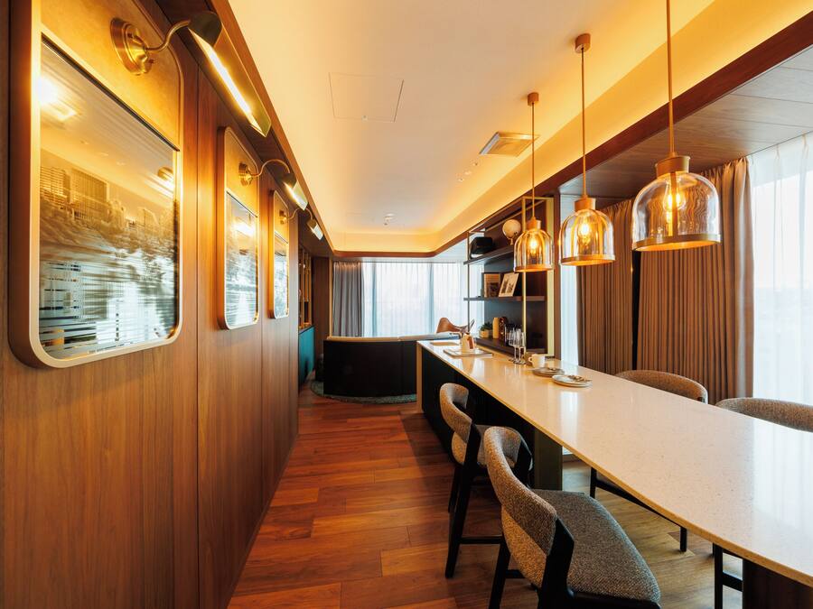 A modern kitchen with wooden cabinetry, a long countertop, and pendant lighting.
