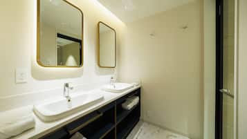 Un baño moderno con dos lavamanos, un espejo y una ducha.