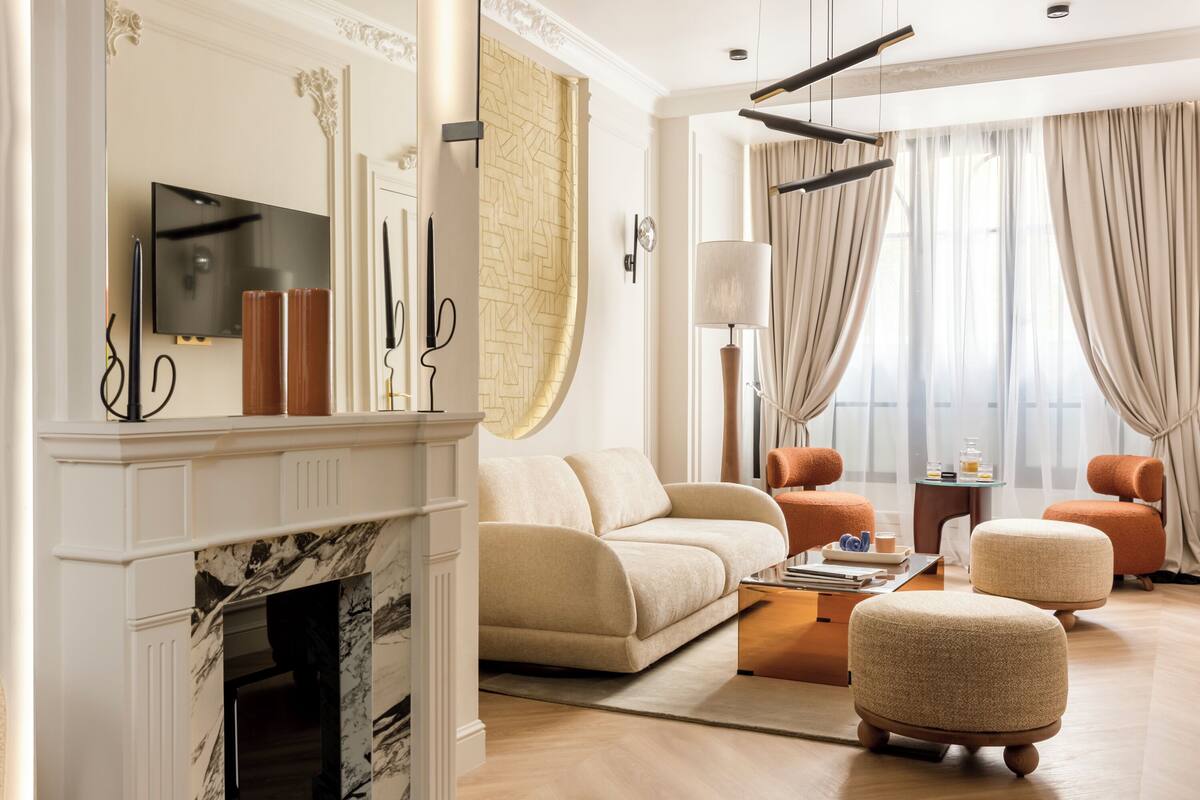 A modern living room with a fireplace, a sofa, ottomans, a coffee table, and a TV mounted on the wall.