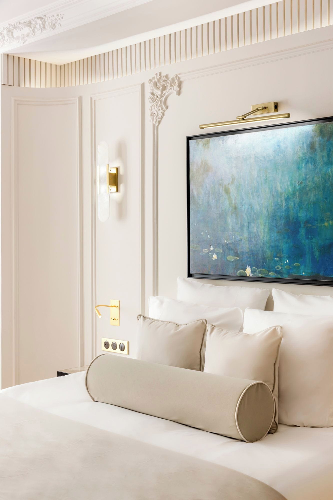 Une chambre d’hôtel avec un grand lit, des murs blancs, un plafond décoratif et un grand tableau abstrait.