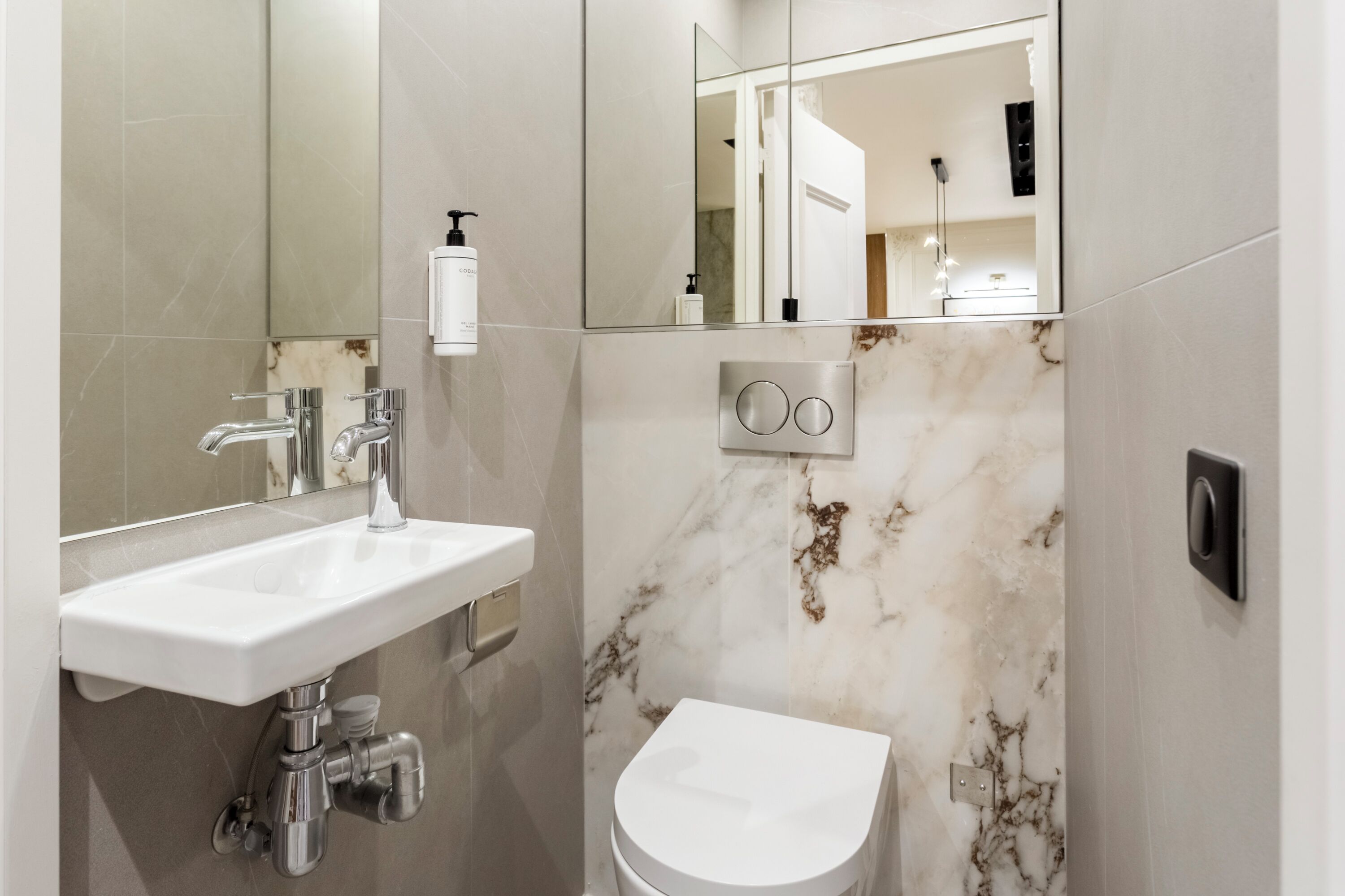 Une salle de bain moderne avec un lavabo blanc, un robinet chromé et un mur en marbre.