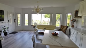 Ett rymligt kök med en stor TV, en matplats med bord och stolar samt en bekväm sittgrupp med en soffa.