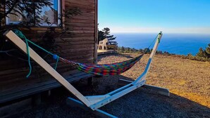 Un hamac sur une terrasse en bois, avec vue sur l’océan.