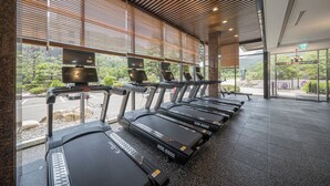 A row of treadmills with a view of a parking lot and greenery outside. - Bugok Royal Hotel (Changnyeong)
