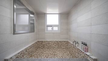A modern bathroom with a mosaic tile floor, a built-in window, and a vanity with toiletries.