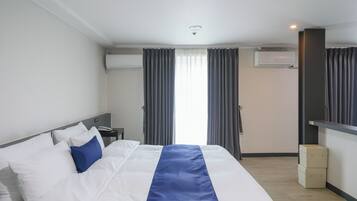 Una camera d'albergo con un letto, un comodino, un condizionatore e una finestra con tende.