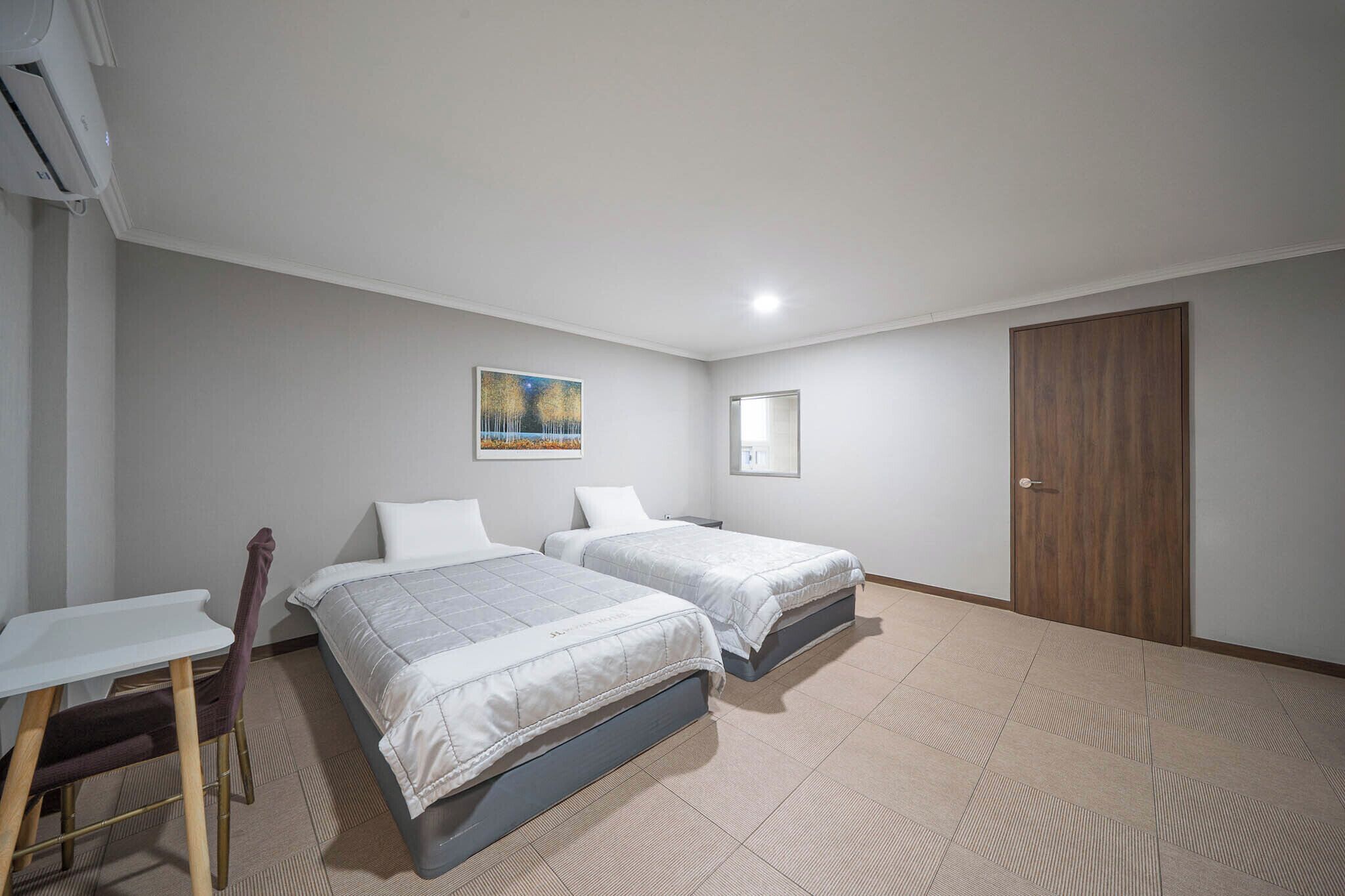 Una habitación con dos camas, un escritorio y una silla.