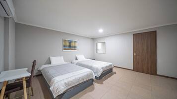 Una habitación con dos camas, un escritorio y una silla.