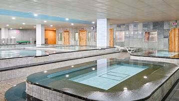 A large indoor swimming pool with multiple lanes, a separate hot tub area, and a reception desk.