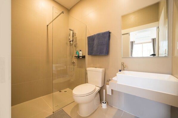 Une salle de bain moderne avec une douche à parois de verre, des toilettes et un lavabo blanc avec un miroir au-dessus.
