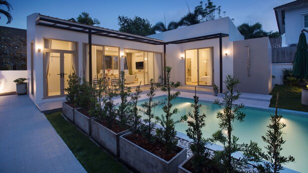 A modern house with a swimming pool, large windows, and a patio area.