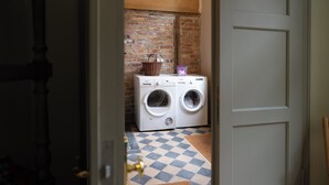 A laundry area with a washing machine and dryer, a brick wall, and a checkered floor. - Spend the night in a monument in the middle of Halberstadt's old town (Halberstadt)