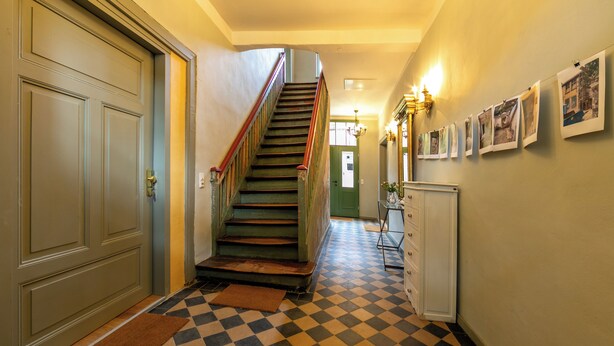 A hallway with a checkered floor, a staircase with a red handrail, and a door with a green frame. - Spend the night in a monument in the middle of Halberstadt's old town (Halberstadt)