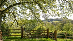 Une porte en bois mène à un paysage verdoyant et luxuriant, avec une colline en arrière-plan.