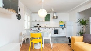 Une cuisine moderne avec des meubles blancs, une table ronde en verre et une chaise jaune.