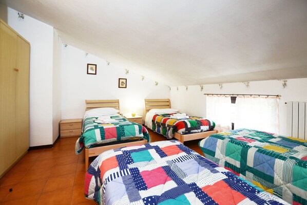 Une chambre avec deux lits simples, une armoire en bois et une table de chevet avec une lampe.