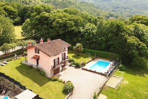 A two-story house with a swimming pool, surrounded by lush greenery and hills. - Casa Lina (Colico)