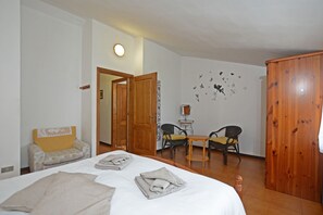 Un dormitorio con una cama, dos sillas, una mesita y un armario.