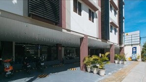 A building with a covered entrance, potted plants, and a clear sky. - Leoncia's Apartelle (Mandaue)