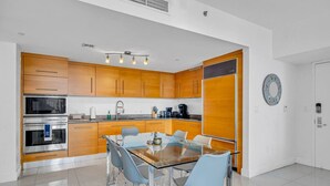 Una cocina moderna con armarios de madera, electrodomésticos de acero inoxidable y una mesa de comedor de vidrio con sillas.