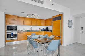 Una cocina moderna con armarios de madera, electrodomésticos de acero inoxidable y una mesa de comedor de vidrio con sillas.