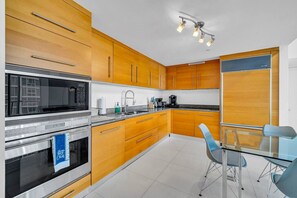 Una cucina moderna con mobili in legno, elettrodomestici in acciaio inossidabile e un tavolo da pranzo in vetro.