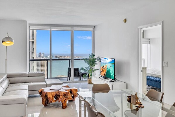 Un soggiorno moderno con un'ampia finestra, un'area pranzo e vista sul mare.