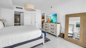 Un dormitorio con cama, televisión, cómoda y espejo.