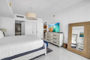 A bedroom with a bed, a TV, a dresser, and a mirror.