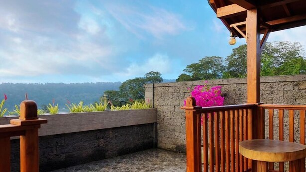 An outdoor wooden deck with a stone wall and a view of the landscape.