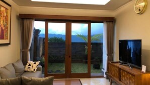 A living room with a sofa, TV, and sliding glass doors leading to a garden.